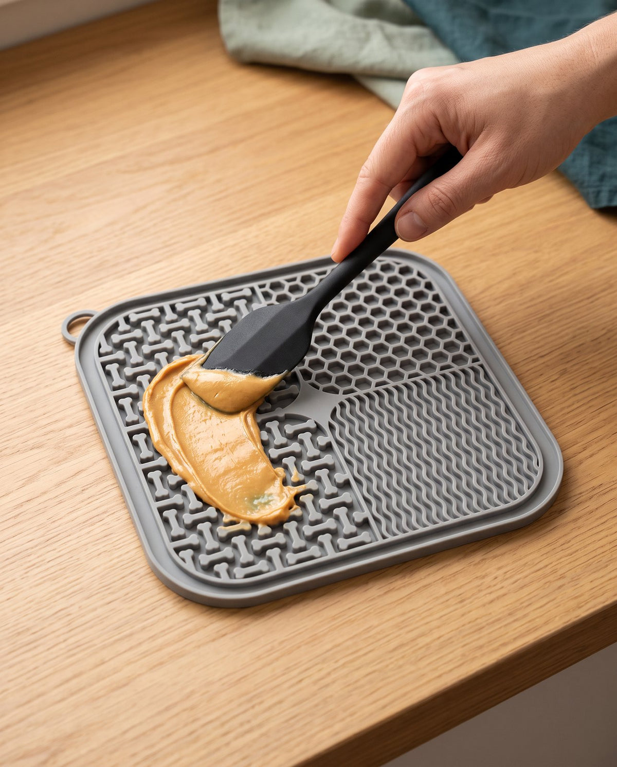 Spreading a pet-safe treat on the PawPawDoo lick mat with the silicone spatula