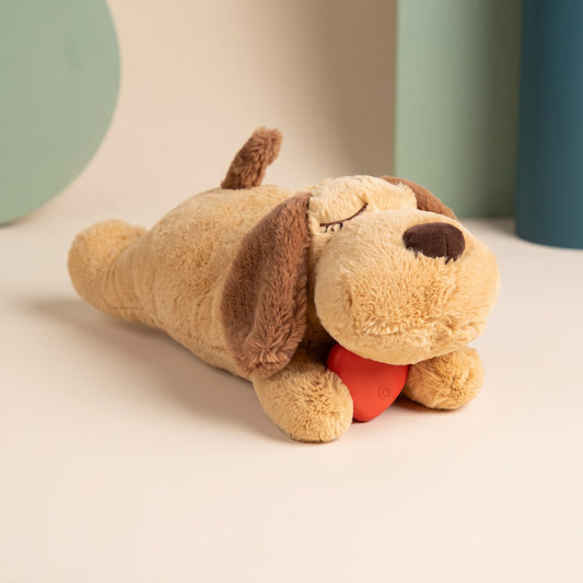 Heartbeat Comfort Plush puppy toy with brown ears lying on a cream surface